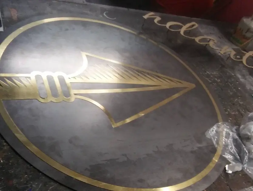 a close up of a metal sign with a gold arrow