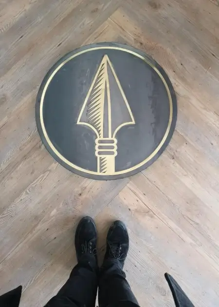 a close up of a person standing on a wooden floor with a black and gold logo