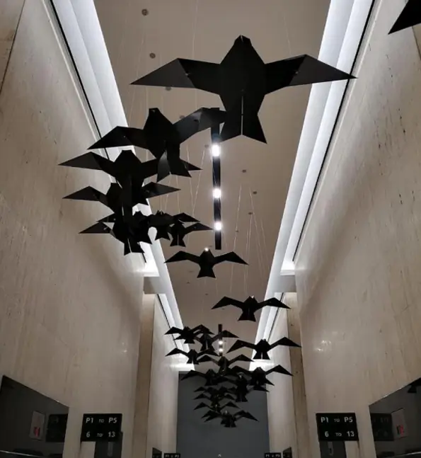 there are many black birds hanging from the ceiling of a building