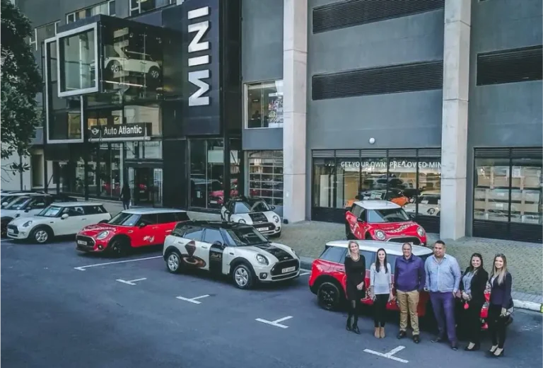 arafed group of people standing in front of a building with mini cars