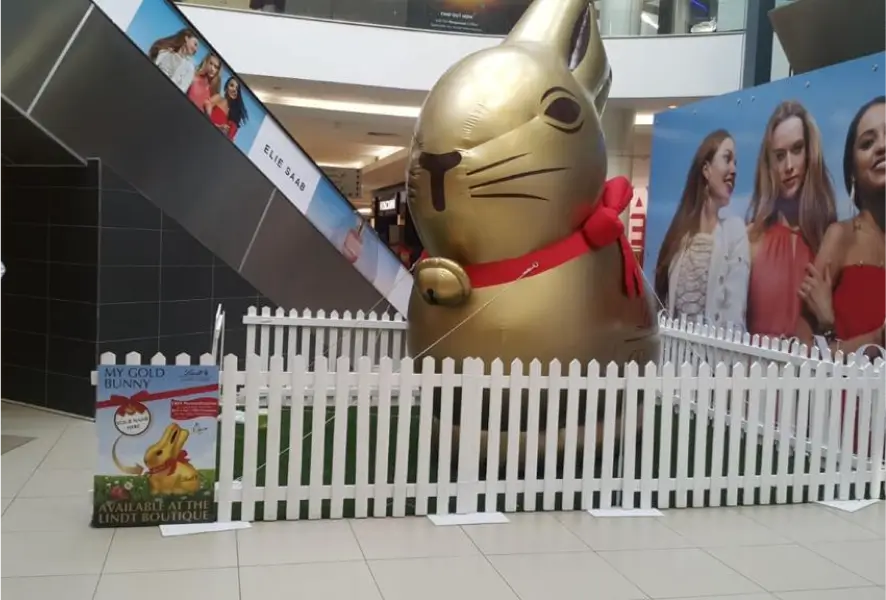 there is a giant cat statue in a mall with a fence