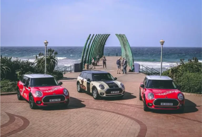 three mini coopers parked on a brick road near the ocean