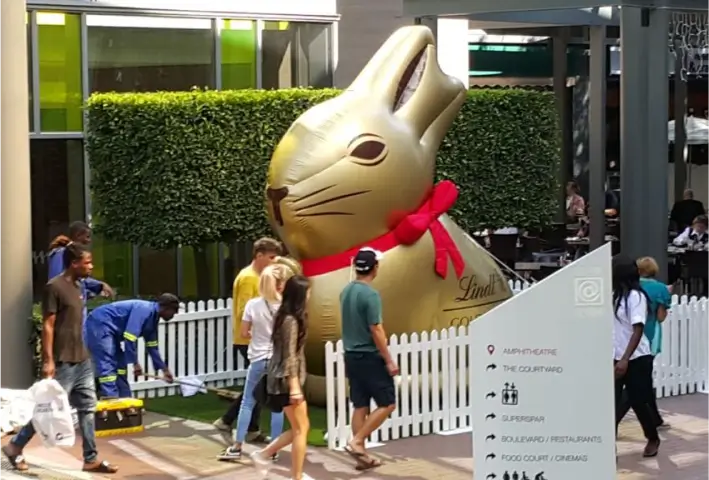 people walking past a giant golden rabbit statue in a shopping mall
