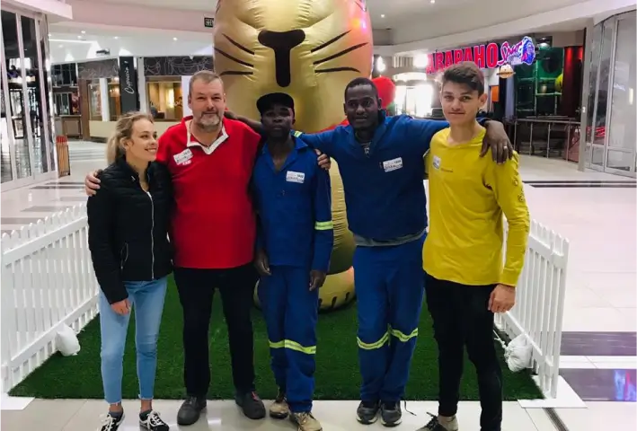 several people standing in front of a giant cat statue in a mall