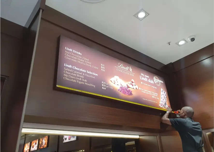 arafed menu board in a restaurant with a man standing in front of it