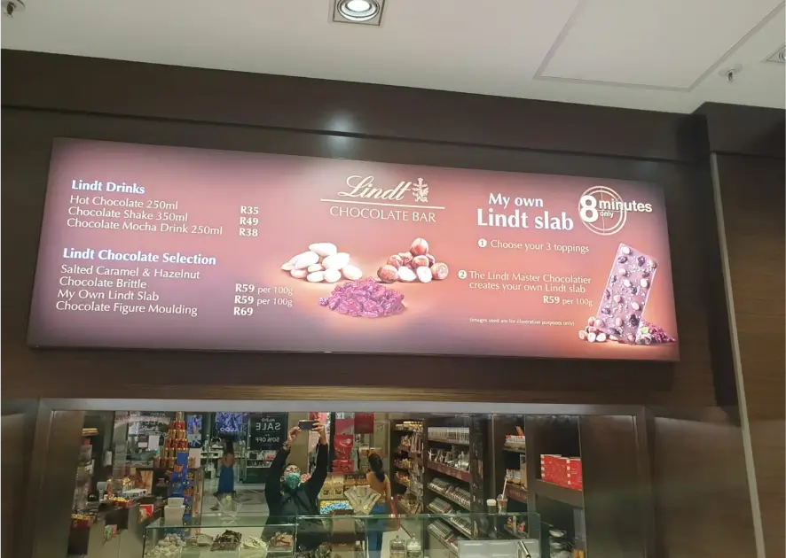 arafed menu of a chocolate shop with a woman standing in front of it