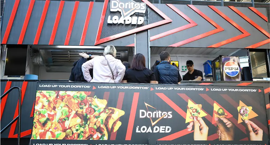 people are standing outside of a donuts loaded truck with a sign