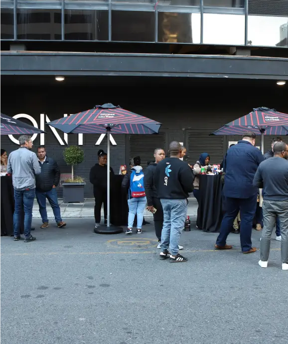 people standing in a parking lot with umbrellas and tables